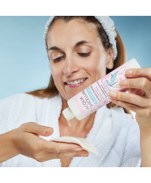 Ragazza versa l'acqua micellare su un dischetto di cotone riutilizzabile