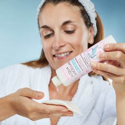 Ragazza versa l'acqua micellare su un dischetto di cotone riutilizzabile