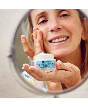 Donna matura applica crema viso notte Deep Care allo specchio