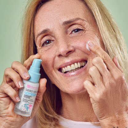 Signora sorridente applica il siero viso antiage